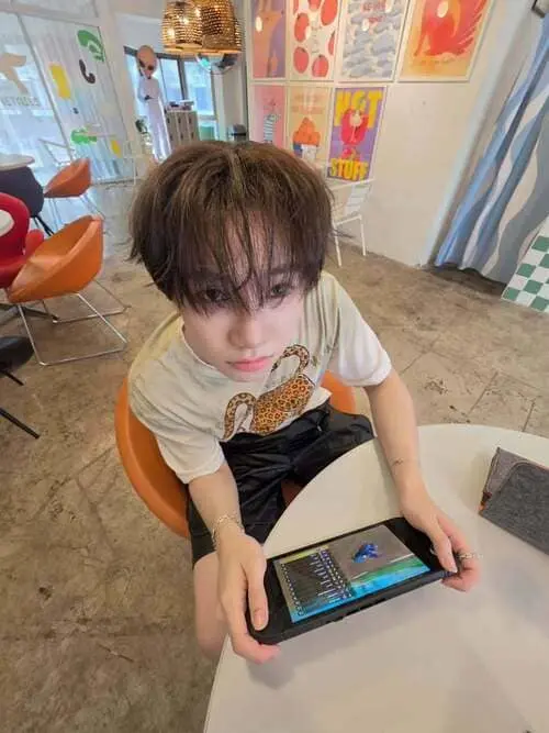 saengnuea-jitaboon-ngamboonyarak-hinh-anh-3 SaengNuea Jitaboon Ngamboonyarak ngồi ghế cam chơi game trên máy chơi game cầm tay, mặc áo thun họa tiết thiên nga