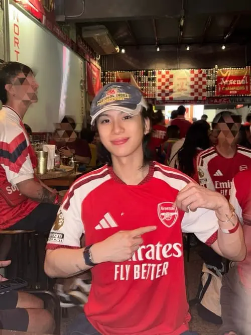 tytan-teepprasan-hinh-anh-3 Tytan Teepprasan mặc áo đấu Arsenal đội mũ lưỡi trai chỉ tay vào logo đội bóng